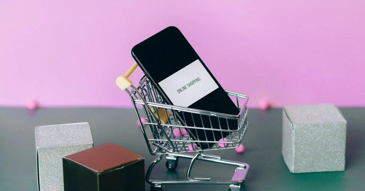 A smartphone with a shopping cart depicting the concept of online shopping in a colorful studio setup.