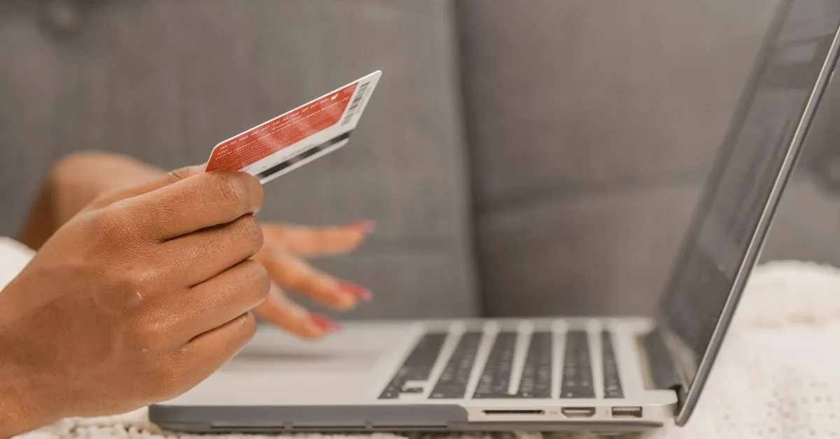 Close-up of a person using a credit card for online shopping on a laptop.