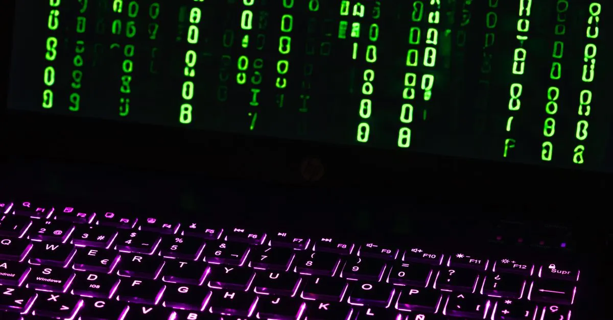 Illuminated laptop keyboard with Matrix-style green code cascading down screen.