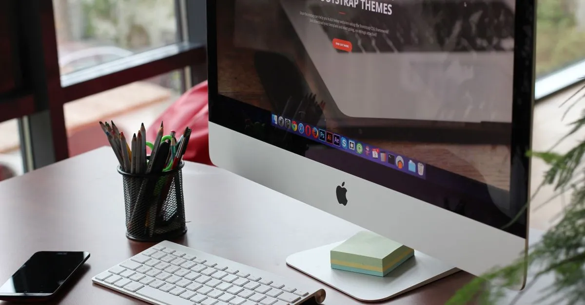 A clean, organized desk setup featuring a computer display, keyboard, and office supplies.