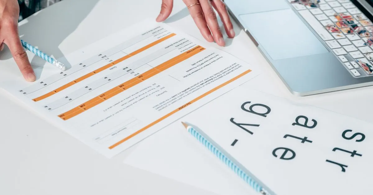 Close-up of hands reviewing business documents and strategy papers on an office desk.