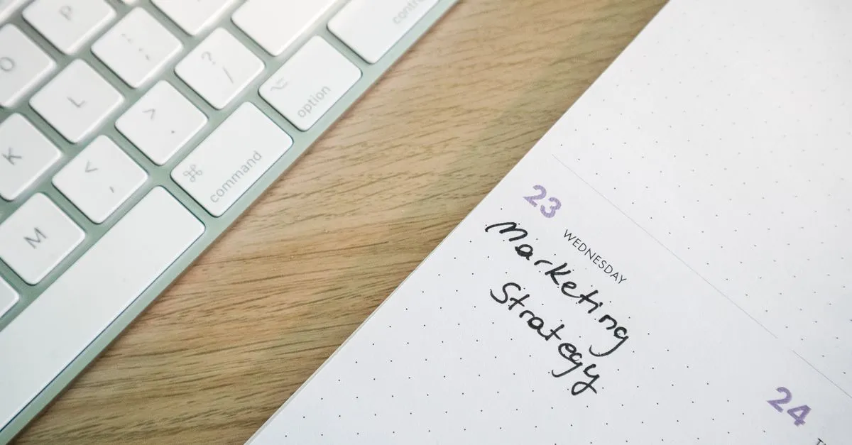 Close-up of a desk with a keyboard and a calendar open to a marketing strategy note.