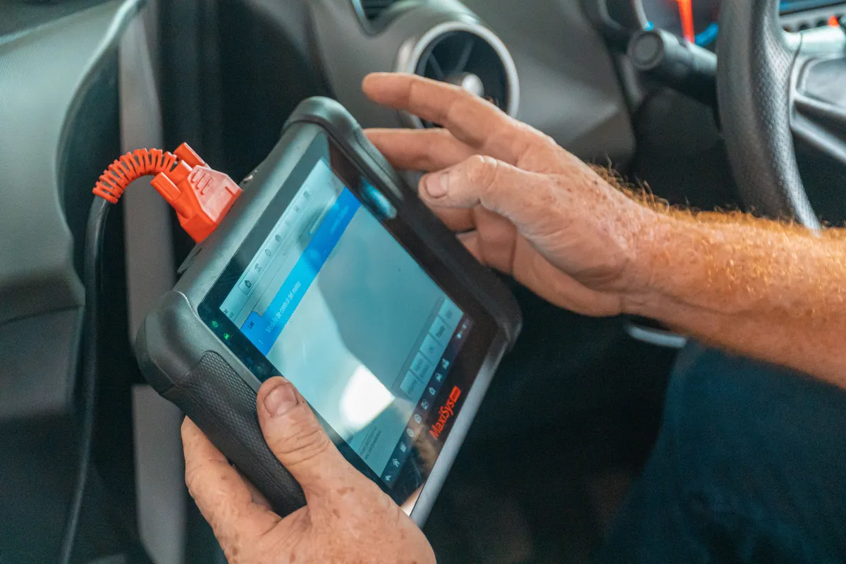 Mechanic using a diagnostic tablet on a car engine