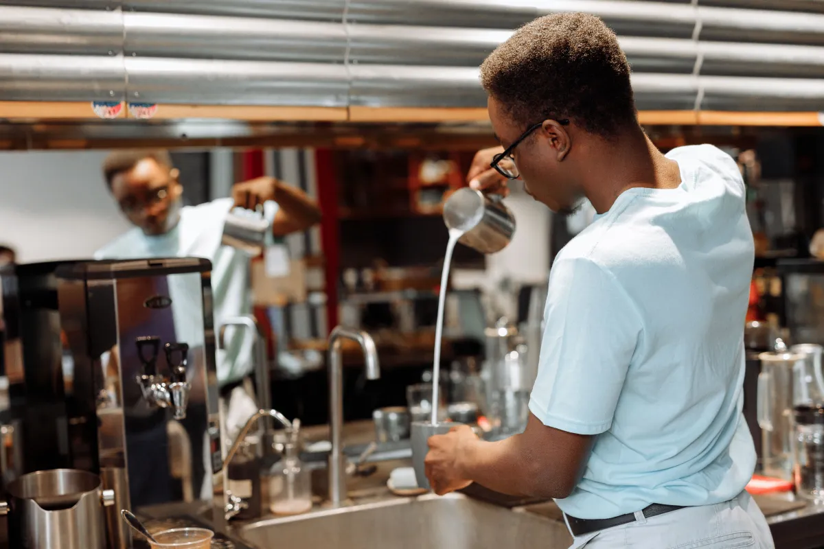 Barista pouring latte art into a cup