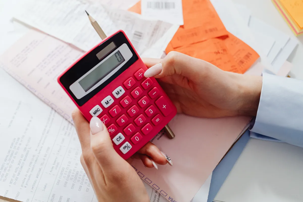 Close-up of hands using a calculator with paperwork